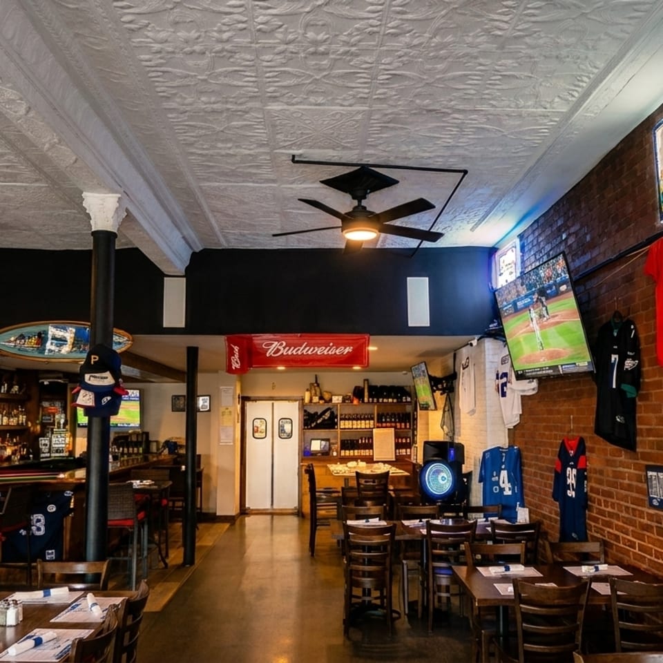 A sports bar interior with brick walls, multiple TVs showing games, and dining tables.